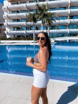 A person holding a drink and standing by a pool

Description automatically generated with low confidence