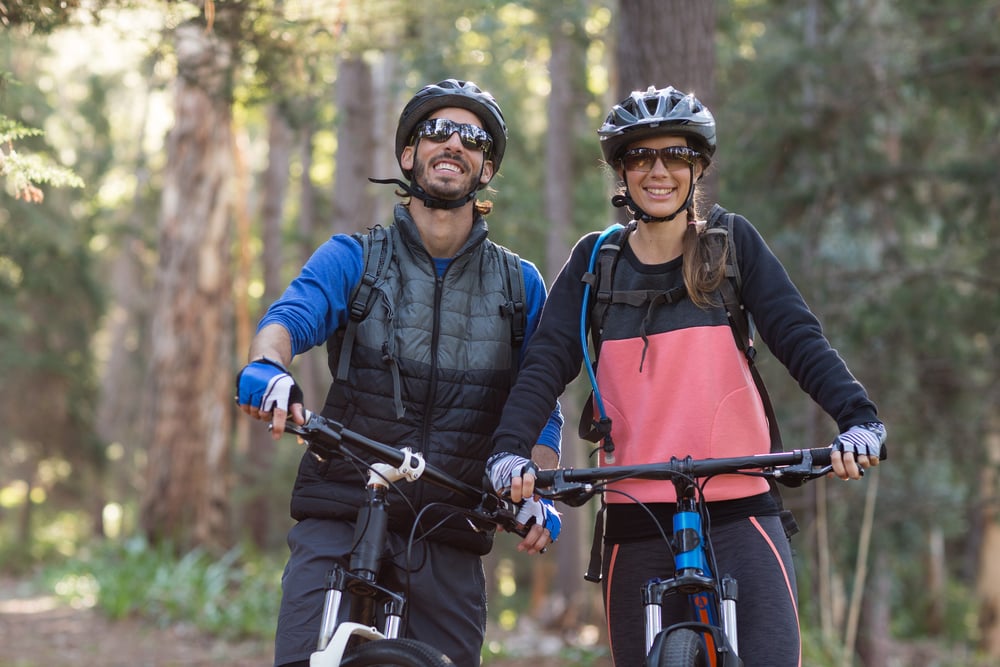 Happy biker couple with mountain bike in countryside