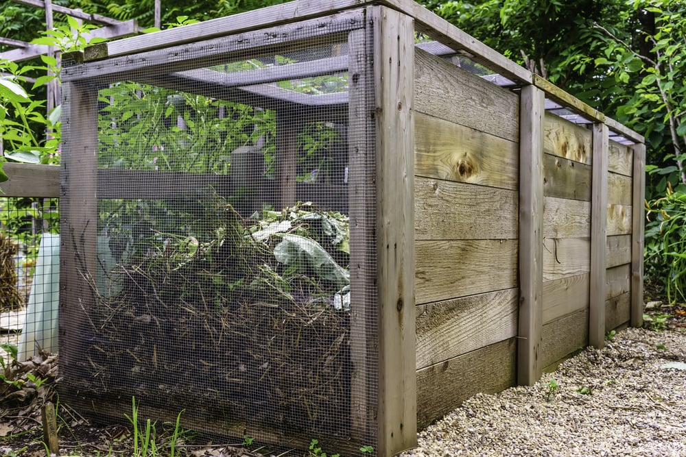 Large compost bin, made of wood and wire mesh, in a community garden, early summer in Illinois, for themes of environment, recycling, organic fertilization-1