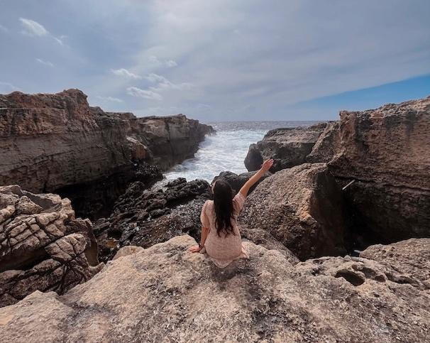 A person sitting on a rock by the ocean

Description automatically generated with medium confidence